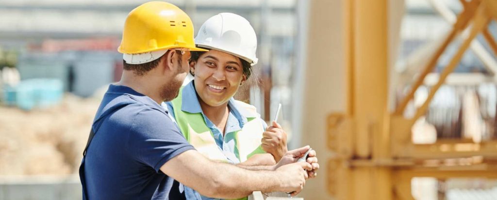 2 contruction workers, one male and one female, engaged in conversation
