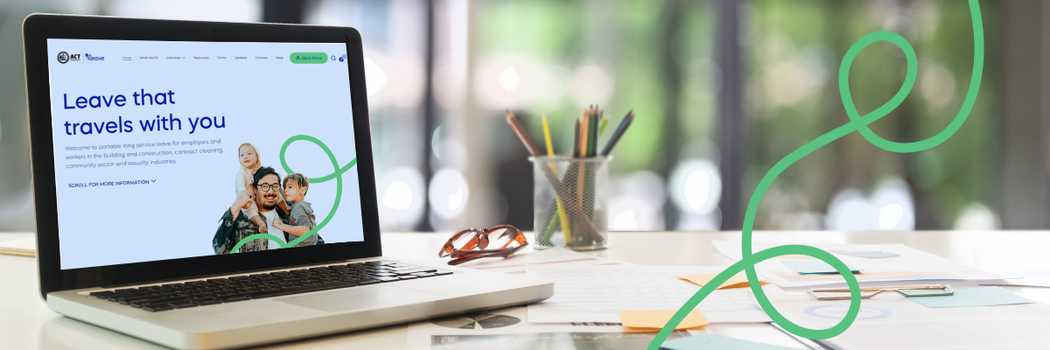 Image of a laptop with the ACT Leave website on the screen, sitting on a desk with papers, glasses and a pencil holder with coloured pencils in it.